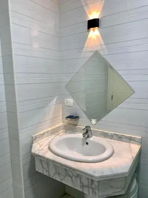 a bathroom sink with a mirror and a light at Turtles Beach Resort - Hurghada in Hurghada