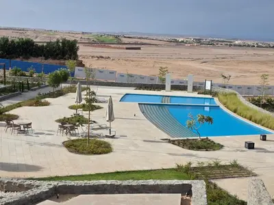 a pool with tables and chairs next to a beach at Jade 18 A in Hurghada