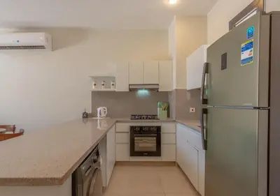 a kitchen with white cabinets and a refrigerator at Calm 3BR House in Shedwan Gouna BBQ, Pool & Lagoon in Hurghada
