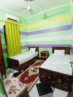 a room with two beds and a colorful striped wall at Hamada guest house in Aswan
