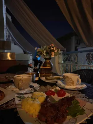 a table with plates of food and a vase of flowers at Orientalna Willa in Hurghada
