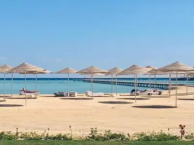 a beach with many straw umbrellas and the ocean at Scandic Resort Hurghada in Hurghada