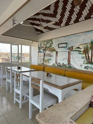 a restaurant with tables and chairs and a painting on the wall at Ekadolli Nubian house- by kerma hospitality in Aswan