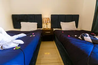 two beds in a hotel room with blue sheets at Fox House Resort in Hurghada