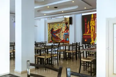 a room with tables and chairs and a large painting on the wall at Fox House Resort in Hurghada