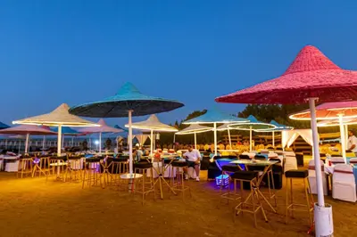 a group of tables and chairs under umbrellas on the beach at Fox House Resort in Hurghada