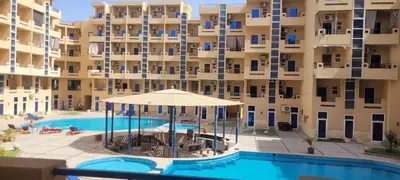 an apartment building with a swimming pool and an umbrella at Gamela in Hurghada