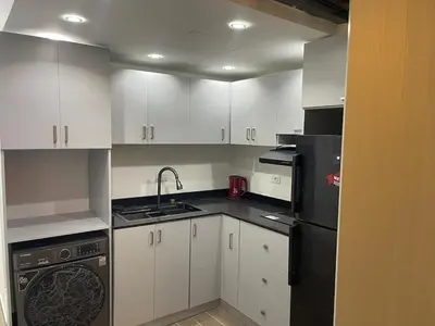a kitchen with white cabinets and a black refrigerator at 1BR Relaxing Seaside Retrear Shal Hasheesh in Hurghada