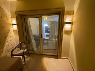 a room with a mirror and a chair and a balcony at 1BR Relaxing Seaside Retrear Shal Hasheesh in Hurghada