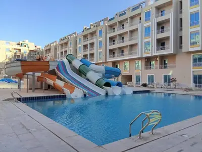 a water slide in a pool in front of a building at Hub resort Aqua park in Hurghada