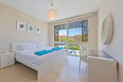 a white bedroom with a bed and a window at Special apartment with Pool and Seasideview, El Gouna in Hurghada