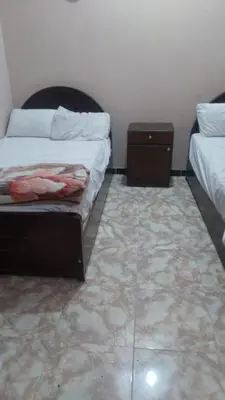 a bedroom with two beds and a tiled floor at The Nile apartment in Luxor