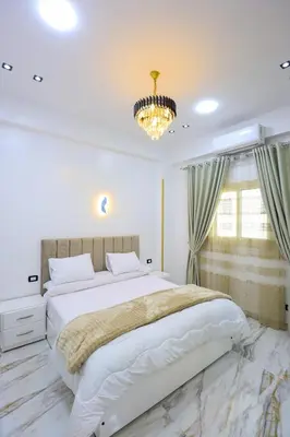 a bedroom with a large bed and a chandelier at Jeanie's House in Al Karnak