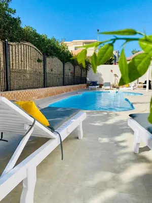 a white bench next to a swimming pool at Magawish Hurghada Apartement 1 in Hurghada