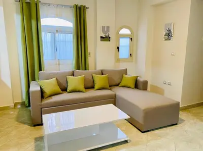 a living room with a brown couch with yellow pillows at Magawish Hurghada Apartement 1 in Hurghada
