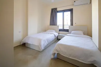 two beds in a room with a window at Bayt Hassan A11 - 2 bedrooms spacious appartment in Hurghada