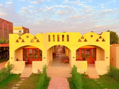 a yellow building with an archway in a yard at Nile Compound Garden in Al Aqālitah
