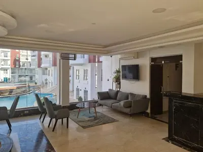 a living room with a couch and a table and a tv at Cozy one bedroom apartment in AquaPalms resort in Hurghada