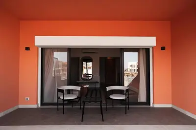 a room with chairs and a table with orange walls at Serene 1BR Haven Kamaran in Hurghada