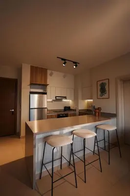 a kitchen with three bar stools and a counter at Shedwan Sky Loft Rooftop Escape with Pool View in Hurghada