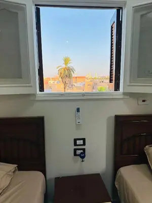 a window in a room with two beds and a palm tree at Habob Nubian Guest House in Aswan