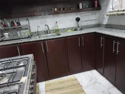 a kitchen with wooden cabinets and a sink and a stove at فيلا مبارك الغردقه البحر الاحمر in Hurghada