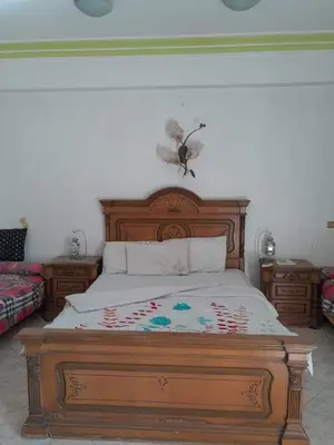 a bedroom with a wooden bed with a butterfly on the wall at Nube's dream house in Luxor