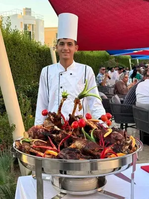 a man in a chefs hat standing next to a barbecue grill at Hurghada Fanader Bay Lever111 in Hurghada