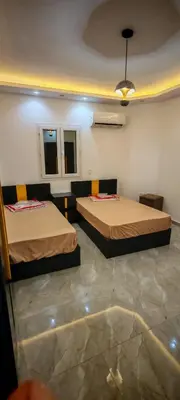 two beds in a room with two windows at فيلا بجوار سينزو مول in Hurghada