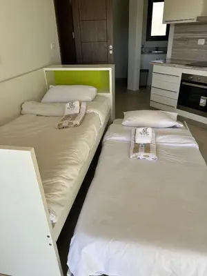 two beds in a kitchen with white sheets and pillows at G cribs cozy studio in El Gouna