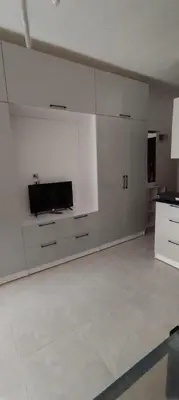 a kitchen with white cabinets and a flat screen tv at Fiesta resort in Hurghada