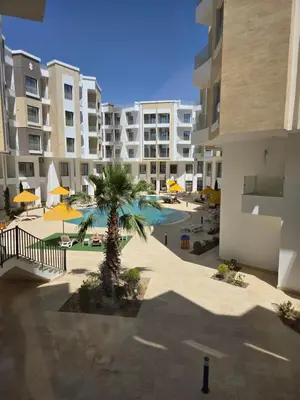 an apartment complex with a palm tree and a swimming pool at Aqua infinity in Hurghada