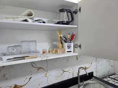 a kitchen with a sink and shelves with utensils at Sheraton - New & Stylish Flat in Hurghada