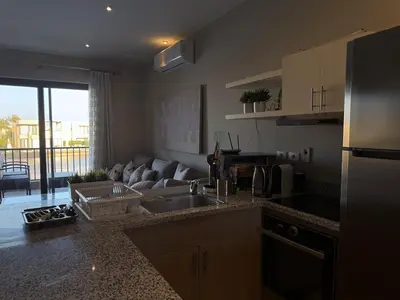 a kitchen with a sink and a living room with a couch at Panoramic 2BR Apt-Free Pool And Lagoon Access At ElGouna in Hurghada