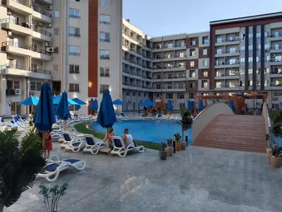 two people sitting in chairs by a pool in a hotel at Tiba Golden Resort Hurghada in Hurghada