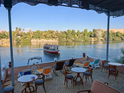 a boat on a river with tables and chairs at Villa Swenet in Aswan