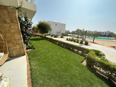 a garden with grass and bushes next to a building at Ground Modern Apartment in Hurghada