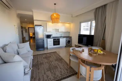 a living room with a table and a kitchen at Breeze, Golf & Sea, 2 BR Luxury Apt with Terrace, Somabay in Hurghada