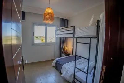 a bedroom with two bunk beds and a chandelier at Breeze, Golf & Sea, 2 BR Luxury Apt with Terrace, Somabay in Hurghada