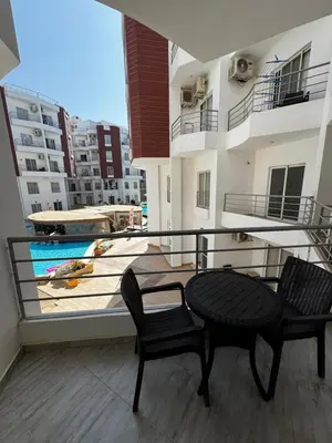 a balcony with two chairs and a table and a pool at Aqua Palms Resort Hurghada in Hurghada