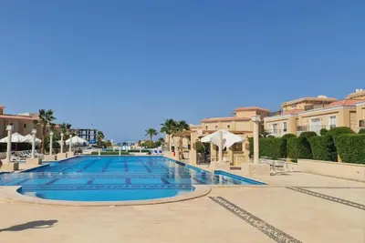 a large swimming pool in a resort with umbrellas at SELENA BAY Luxury Suite beach front hurghada Arena Bar & restaurant سويت فاخر سيلينا باى in Hurghada