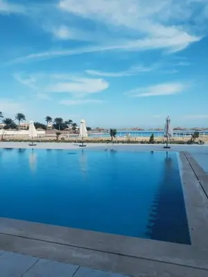 a pool of blue water with umbrellas on a beach at منتجع سكانديك الغردقة in Hurghada