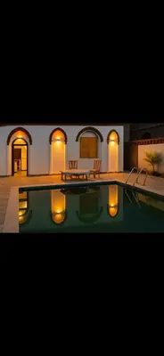 a house with a swimming pool and some chairs at Paradise Apartments in Al Aqālitah