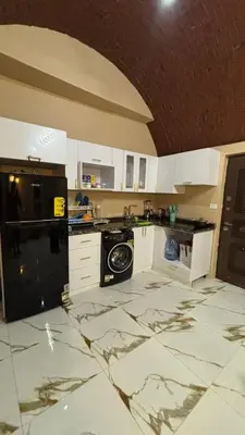 a kitchen with white cabinets and a marble floor at Top in Hurghada