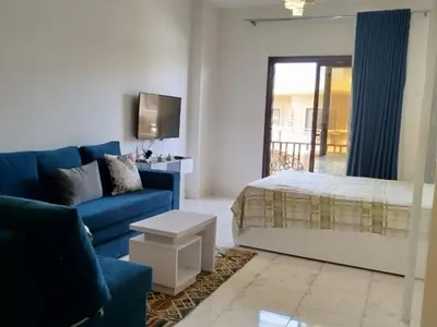 a living room with a blue couch and a bed at Cozy Chalet , Turtles , Side Sea View in Hurghada