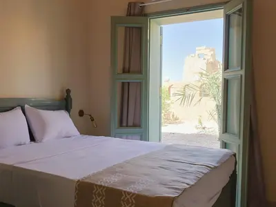 a bedroom with a bed and a sliding glass door at Habu Hotel in Al Aqālitah
