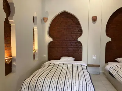 a bedroom with two beds and a brick wall at Sultana Palace in ‘Ezbet Abu Ḥabashi