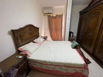 a small bedroom with a bed and a dresser at Elhlal luxury apartment in Hurghada