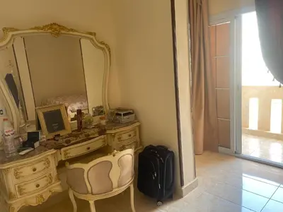 a dressing table with a mirror and a suitcase at Elhlal luxury apartment in Hurghada