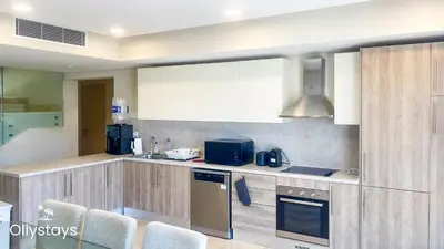 a kitchen with wooden cabinets and a stove top oven at Ollystays Mangrovy Seaview Penthouse 3BR Beach & Pool access in Hurghada
